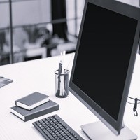 Modern office desk with a blank computer monitor, keyboard, and notebooks, representing Clean Sweep Parking Lot Solutions' professional support team.
