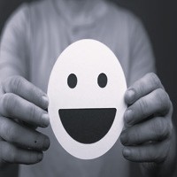 Person holding a smiling face emoji, symbolizing Clean Sweep Parking Lot Solutions' commitment to customer satisfaction and friendly service.