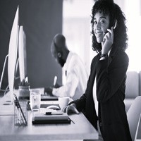 Smiling customer service representative speaking on a headset in a modern office, providing support and assistance.