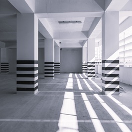 Bright and spacious underground parking garage featuring clean floors and striped safety markings on pillars.
